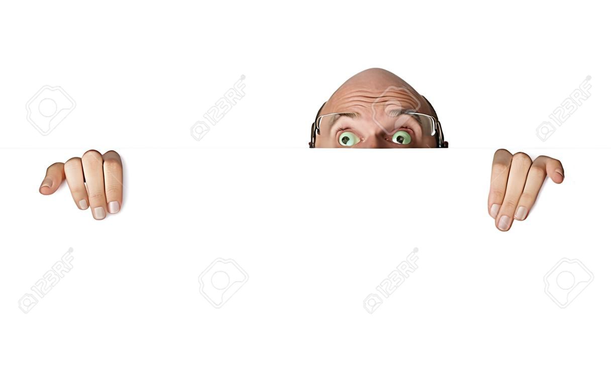 Funny portrait of curious man looking over white wall or sign. Isolated over white.