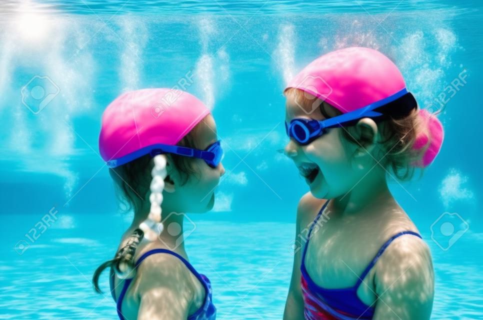 Les enfants nagent sous l'eau dans la piscine, les filles actives et heureuses s'amusent sous l'eau, les enfants font du fitness et du sport pendant des vacances actives en famille