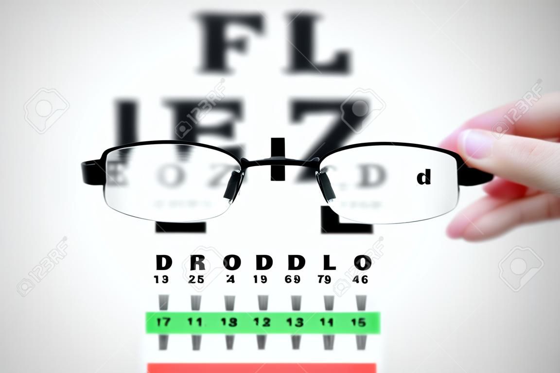 Nő kezében szemüveg látás vizsgálat chart tábla.
