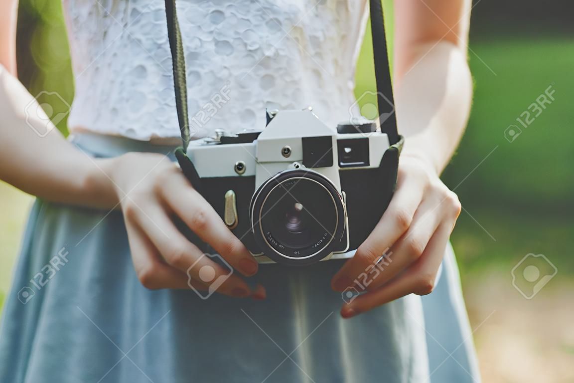 Фото ретро камеры в руках девушки на зеленом фоне размытым