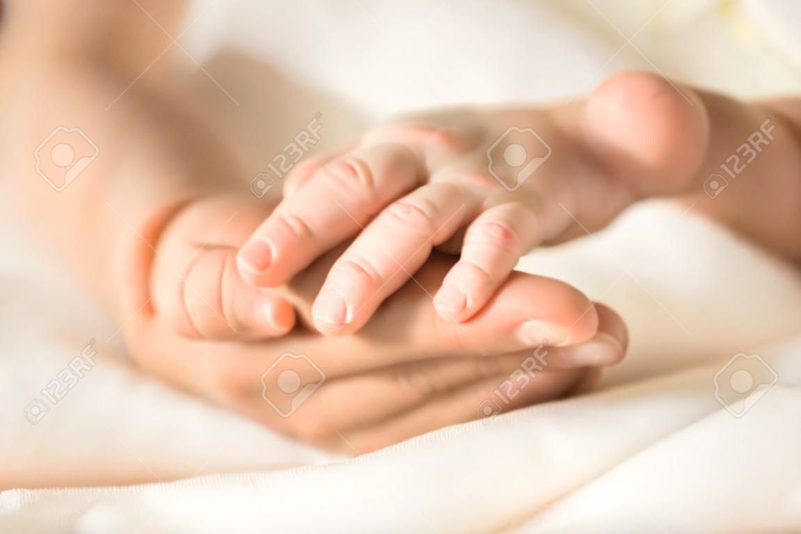 Main féminine tenant la main de son nouveau-né. Maman avec son enfant. Maternité, famille, concept de naissance. Copiez l'espace pour votre texte