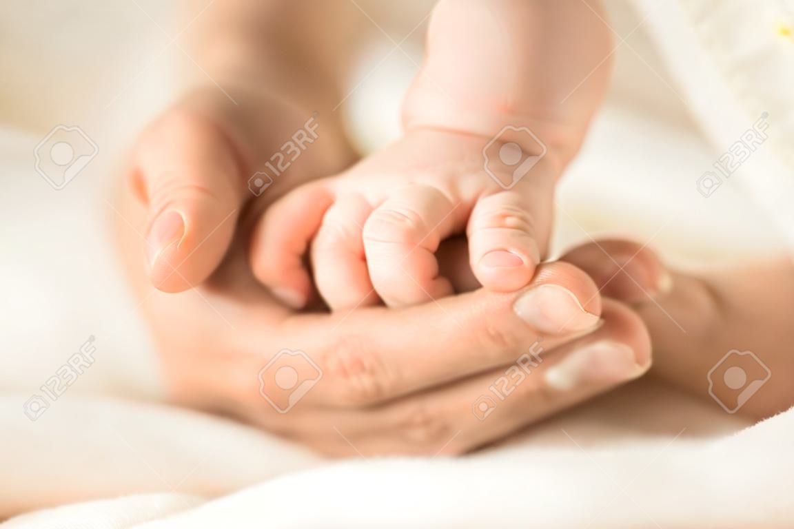 Female hand holding her newborn babys hand. Mom with her child. Maternity, family, birth concept. Copy space for your text