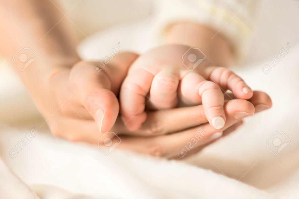 Female hand holding her newborn babys hand. Mom with her child. Maternity, family, birth concept. Copy space for your text