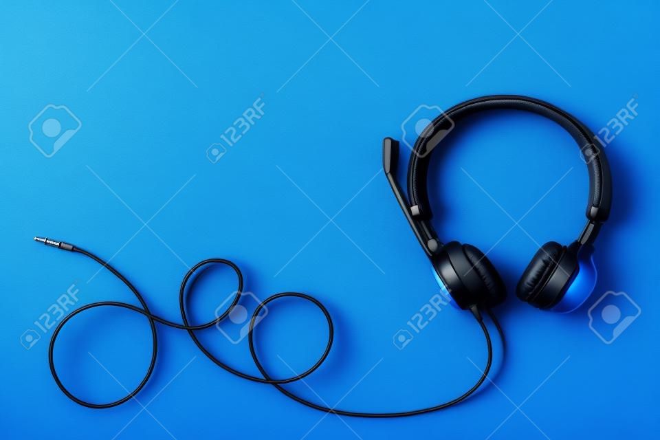 Style black headphones on blue background. Top view. Copy space. Music and sound concept. Urban summer time.