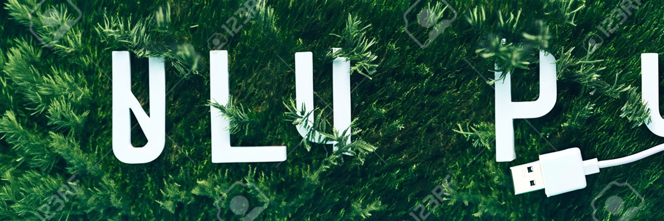 Word Unplug、苔の上の白いインターネットUSBアダプター、緑の草の背景。上面図。スペースをコピーします。バナー。親生命仮説。自然の背景