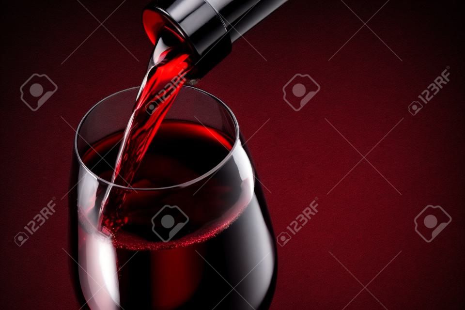 木製の背景に対してグラスに赤ワインを注ぐ