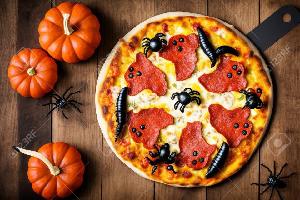 Pizza de Halloween con fantasmas y arañas, arriba escena con decoración sobre un fondo de madera rústica