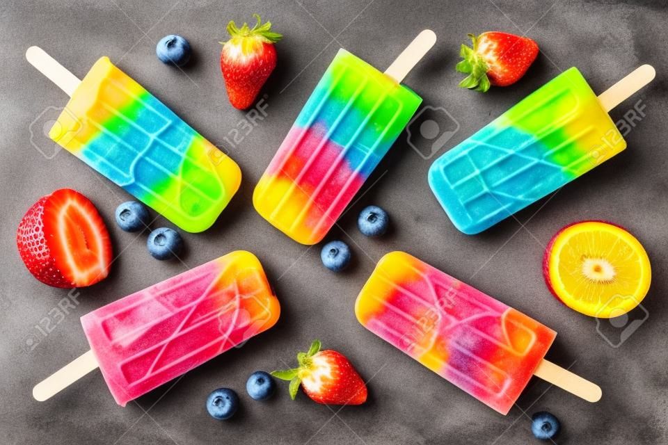 Healthy mixed fruit summer popsicles, top view scattered on a rustic dark