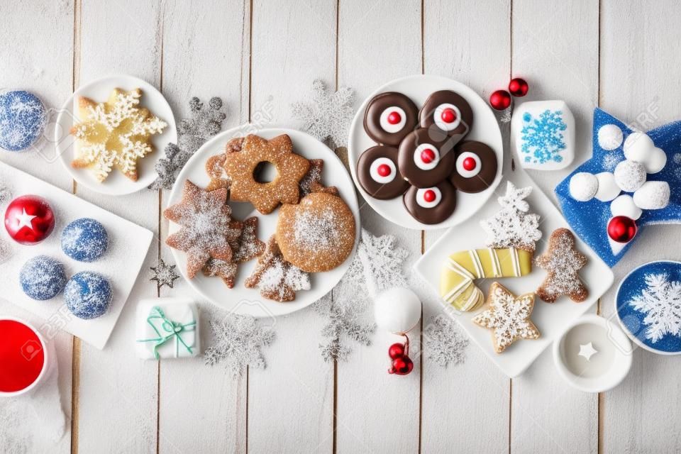 Christmas sweets and cookies. Overhead view table scene over a white wood background. Holiday baking concept.