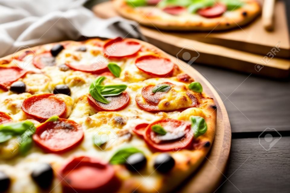 Delicious freshly baked pizzas close up on the wooden board, Ita