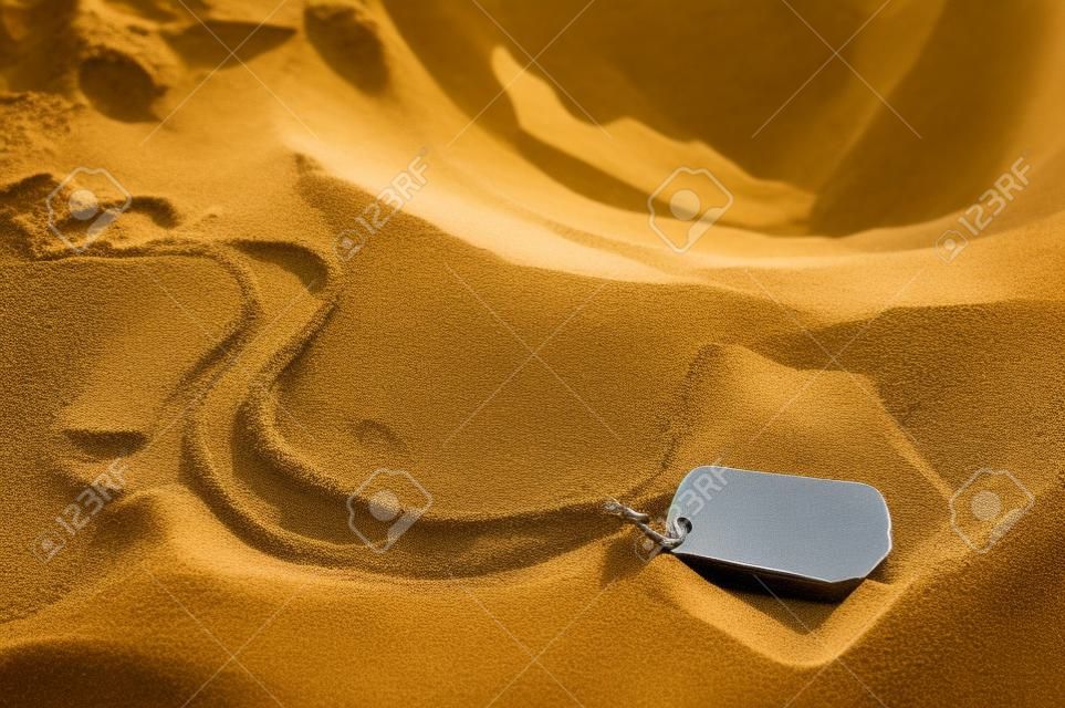 dog tag and helmet in sand