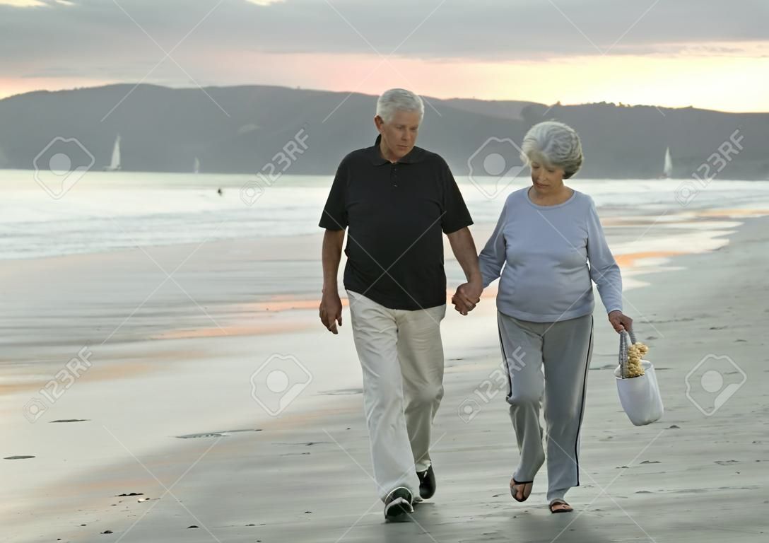 Anziano marito e moglie, passeggiando lungo la spiaggia in California