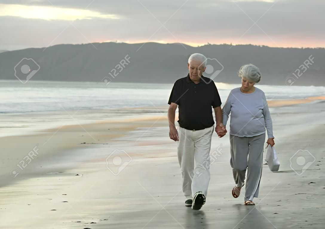 Senior marido y mujer caminando por la playa de California