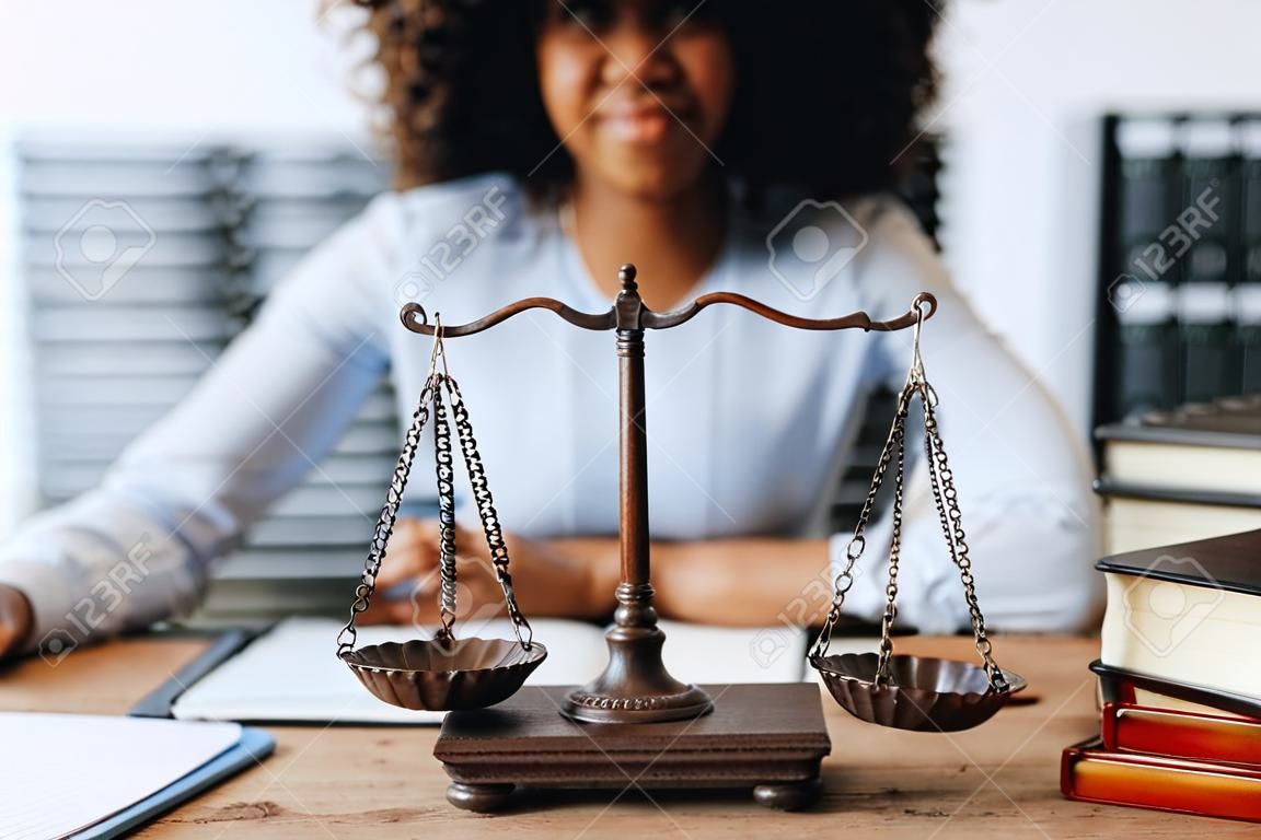 Junge afroamerikanische Anwältin studiert den Fall eines Mandanten und hält den Hammer in einer symbolischen Geste gegen ihre Gegnerin in Gerichts- und Anwaltskonzepten