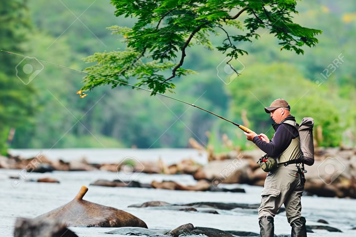 El hombre pesca con mosca en el río Jacques-Cartier, en Parc national de la Jacques-Cartier, Quebec.