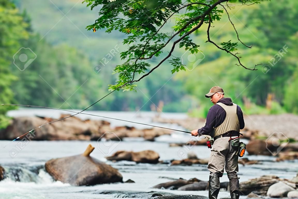 El hombre pesca con mosca en el río Jacques-Cartier, en Parc national de la Jacques-Cartier, Quebec.