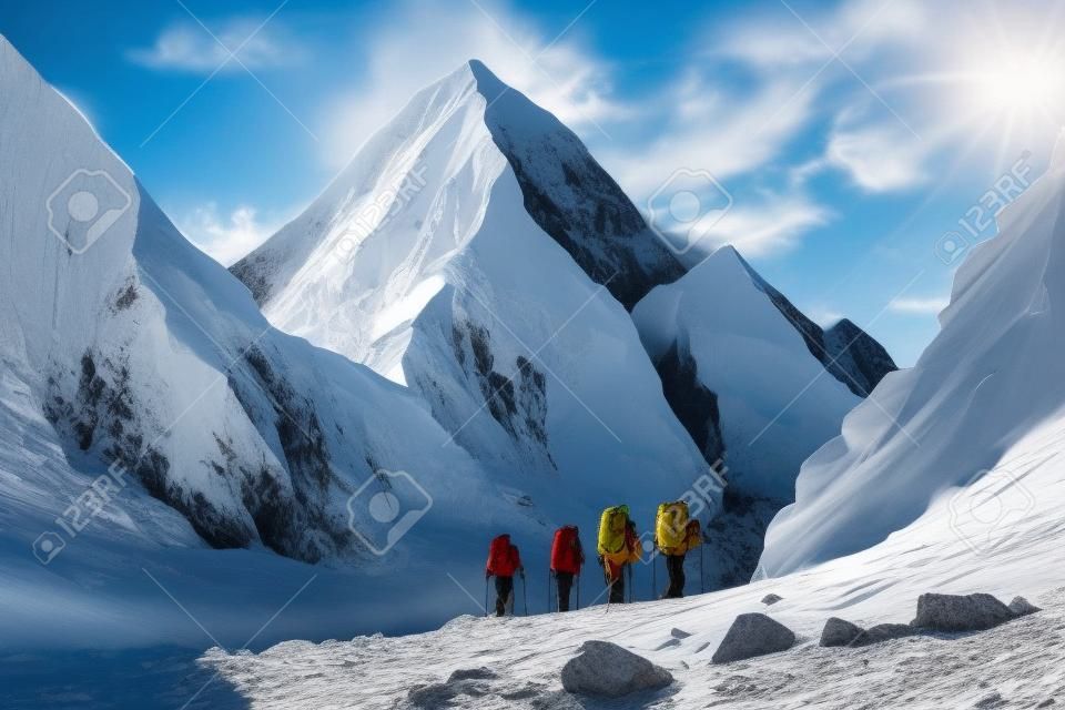 A group of mountaineers adventuring in the beautiful snowcapped mountain range, hiking and climbing to reach its summit for leisure activity.