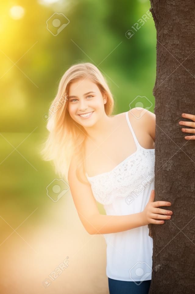 Odkryty portret cute nastolatka za drzewem w lecie