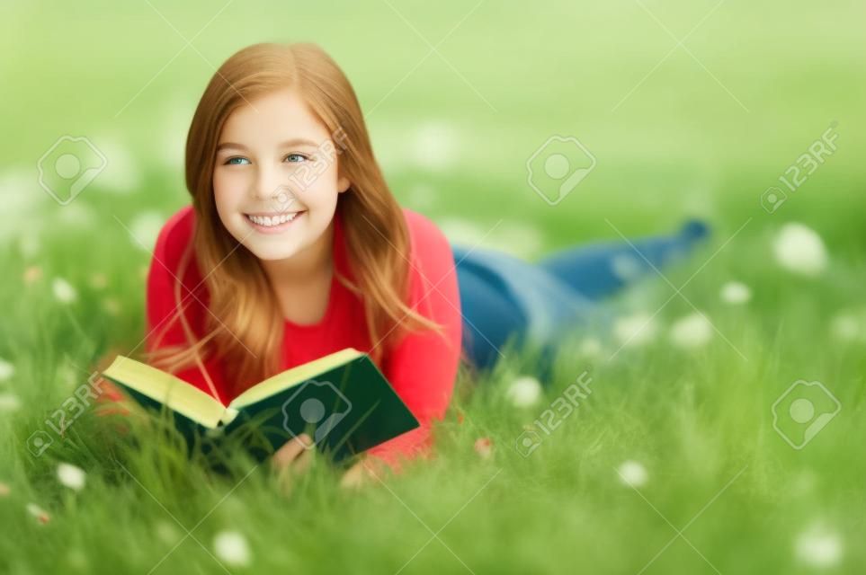 Outdoor Portrait von ein hübsch jugendlich, ein Buch zu lesen, beim liegen im grünen Gras