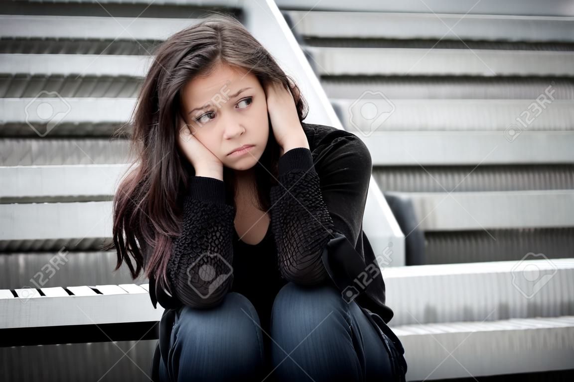 Outdoor ritratto di una ragazza adolescente triste guardando premuroso circa le difficoltà di fronte a un muro grigio