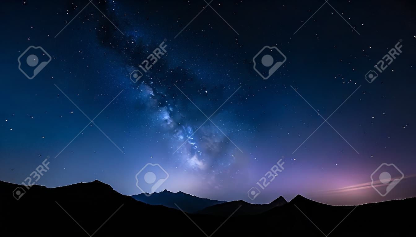 夜空的全景与移动的星星和银河背后的山