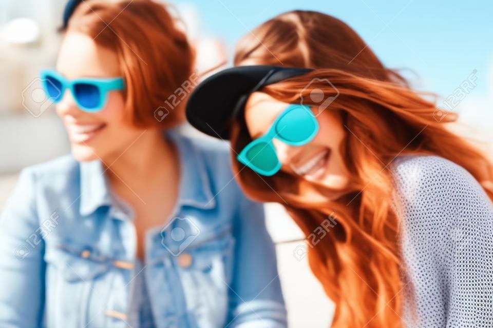 Две красивые девушки счастливым в темных очках на фоне городских