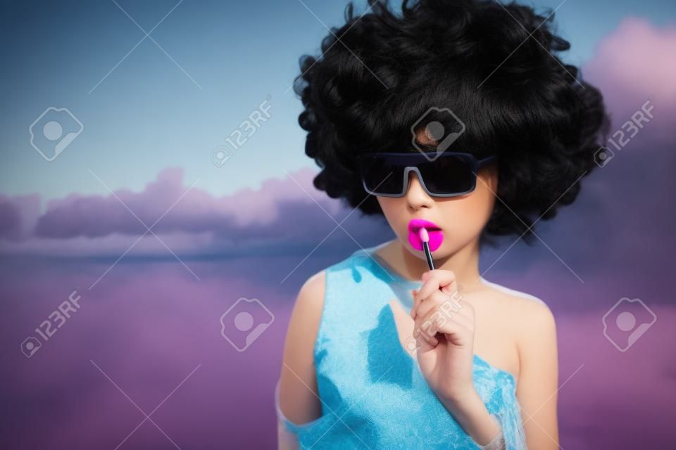girl with black wig hair sucks lollipop. Outdoors lifestyle