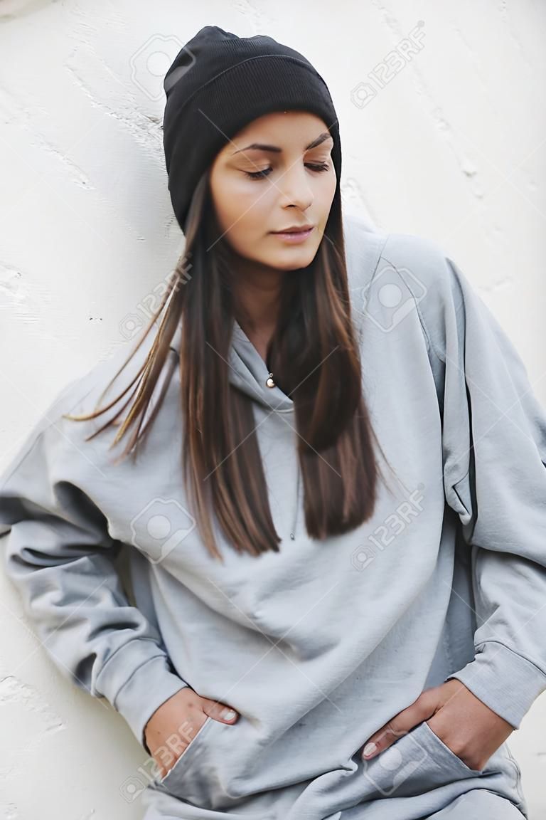 Jong meisje dragen blanco en oversize lange hoodie en zwarte cap. Outdoors lifestyle portret