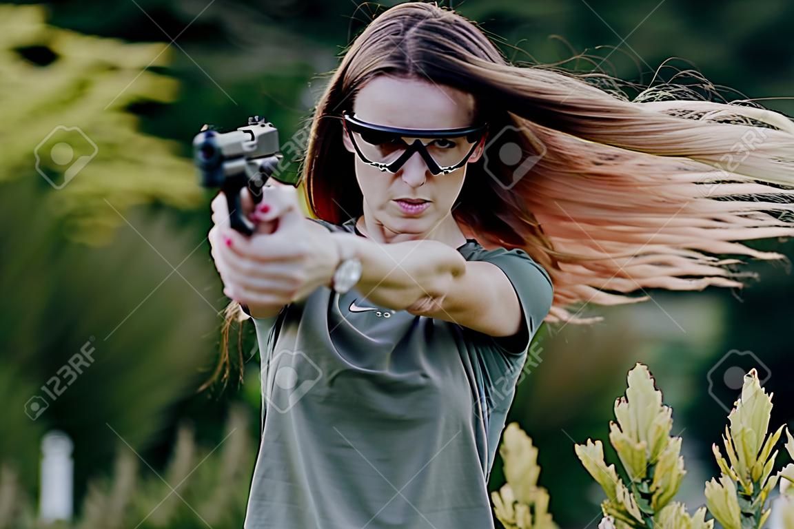 girl on nature learns to shoot a pistol