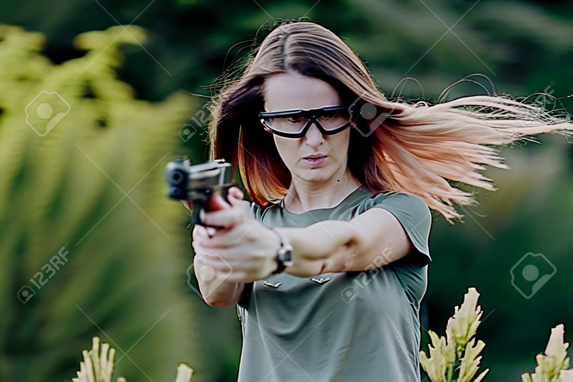 girl on nature learns to shoot a pistol