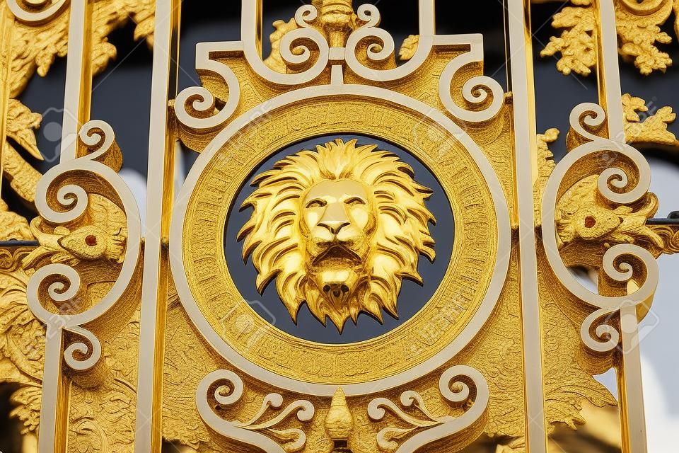 Um medalhão de leão dourado situado em um portão de ferro forjado ornamentado em Paris, França.
