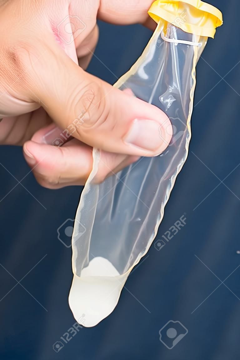 Gebruikt condoom met spermabedrijf in de hand