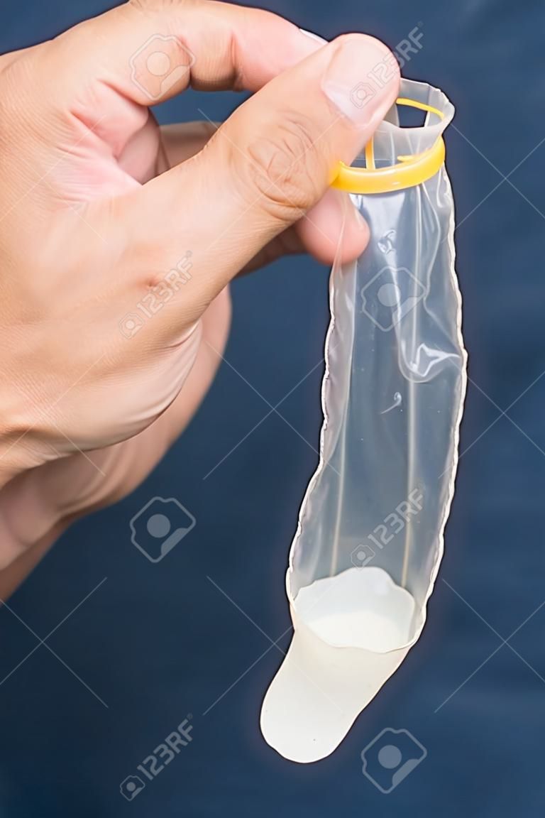 Used condom with semen holding in hand