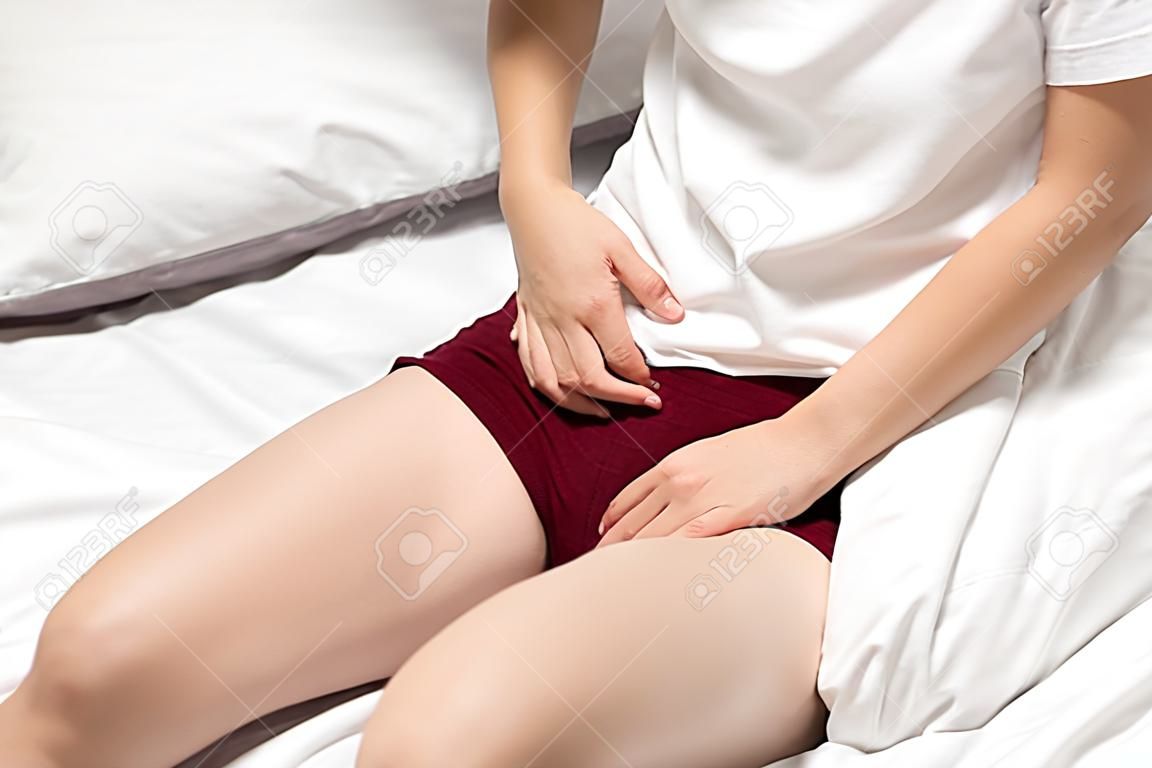 la femme a des douleurs à la vessie et des maux d'estomac assise sur le lit dans la chambre après s'être réveillée se sentant si malade et douloureuse, concept de soins de santé