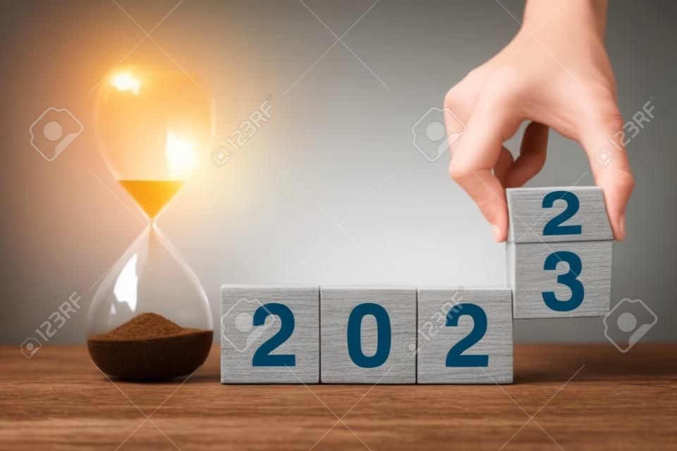 hand flipping blok 2022 tot 2023 tekst met zandloper op tafel. Resolutie, tijd, plan, doel, motivatie, reboot, countdown en nieuwjaar vakantie concepten