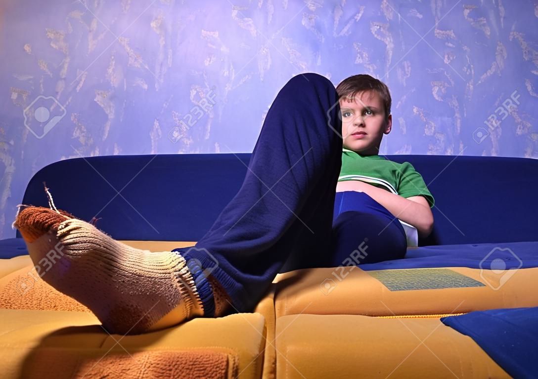 Garçon de porter des chaussettes Sales avec trous dans leur siège sur le canapé
