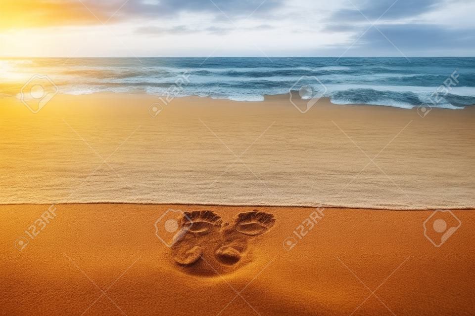 Menschliche barfuß Fußabdrücke im Sand in Richtung Meer warten auf die ankommende Welle, sonnigen bewölkten Sonnenaufgang, aktives gesundes Leben und persönliches Wachstumskonzept, Kopierraum
