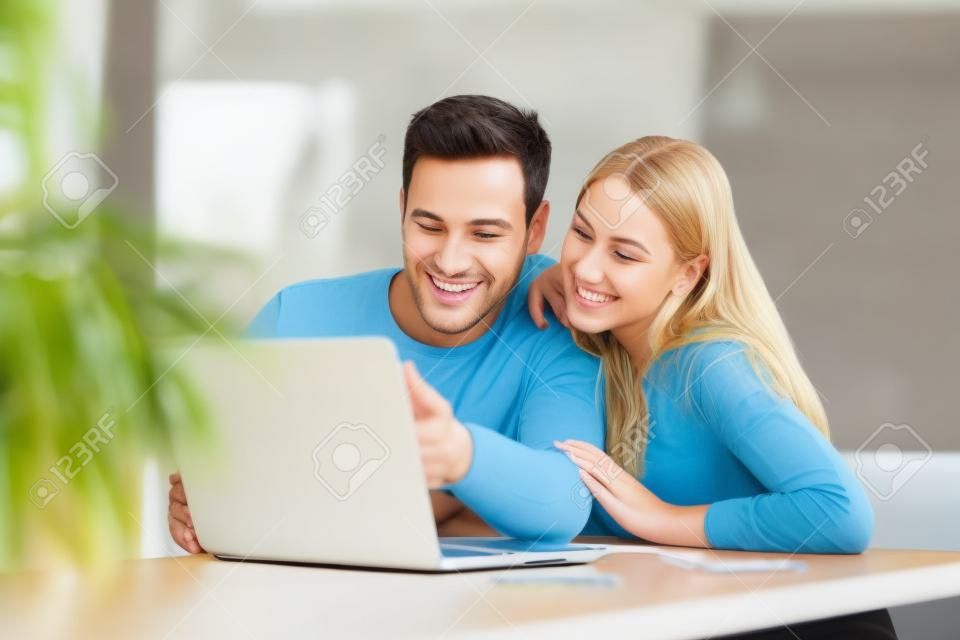 Giovani coppie che per mezzo del computer portatile sullo scrittorio a casa