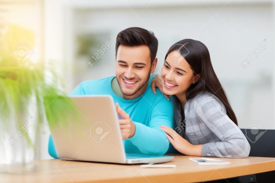 Giovani coppie che per mezzo del computer portatile sullo scrittorio a casa