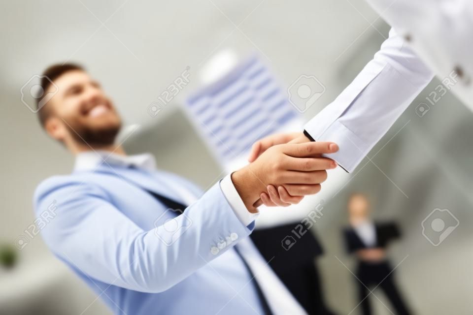 Jeunes gens d'affaires se serrant la main au bureau. Terminer une réunion réussie
