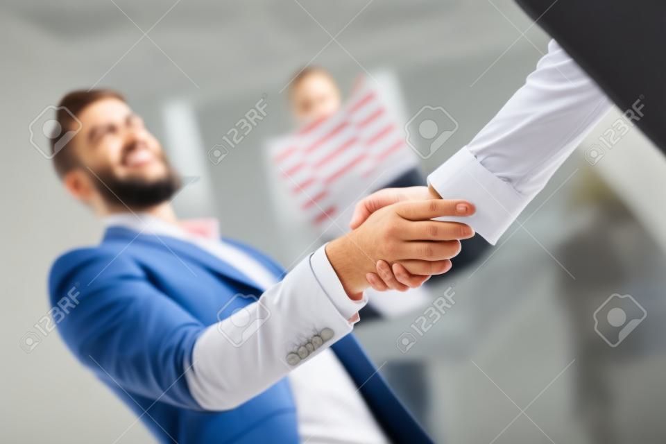 Jóvenes empresarios dándose la mano en la oficina. Terminando una reunión exitosa