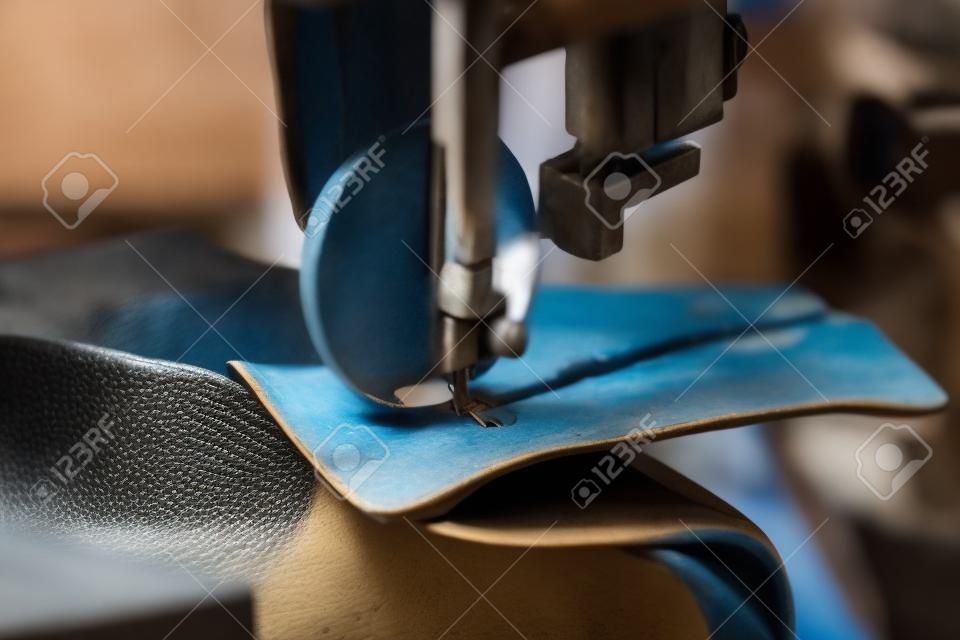 Mãos sapateiro feminino costurando uma parte do sapato na indústria de calçados artesanais