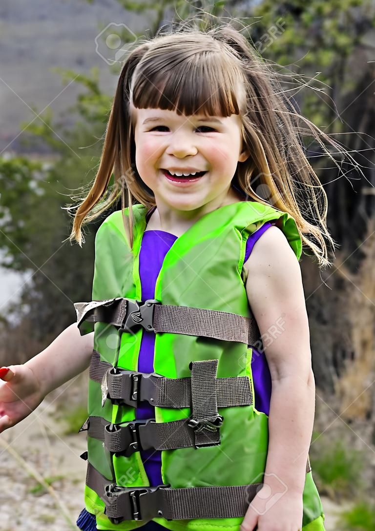 Esta linda menina caucasiana de 3 anos está sorrindo e feliz enquanto brinca ao ar livre.