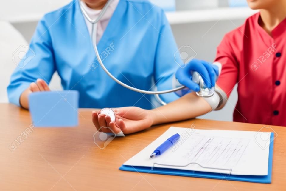 Doctor Measuring arterial blood pressure woman patient on right arm Health care in hospital