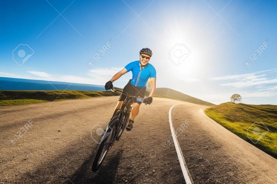 Hombre Ciclista que monta en bicicleta de montaña en un día soleado en una carretera de montaña