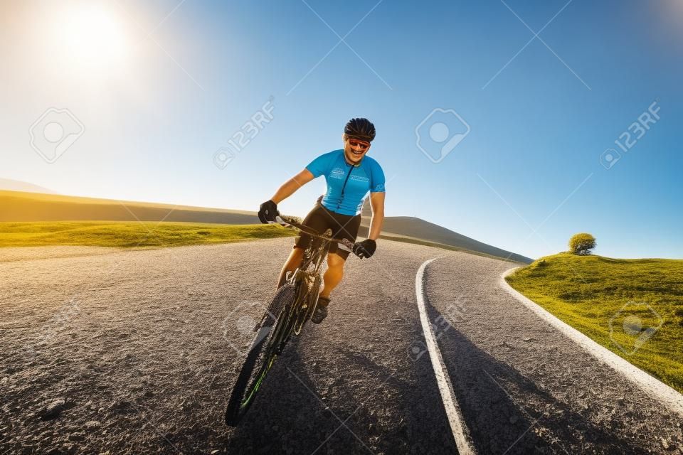騎單車男子在山路騎山地自行車在陽光燦爛的日子