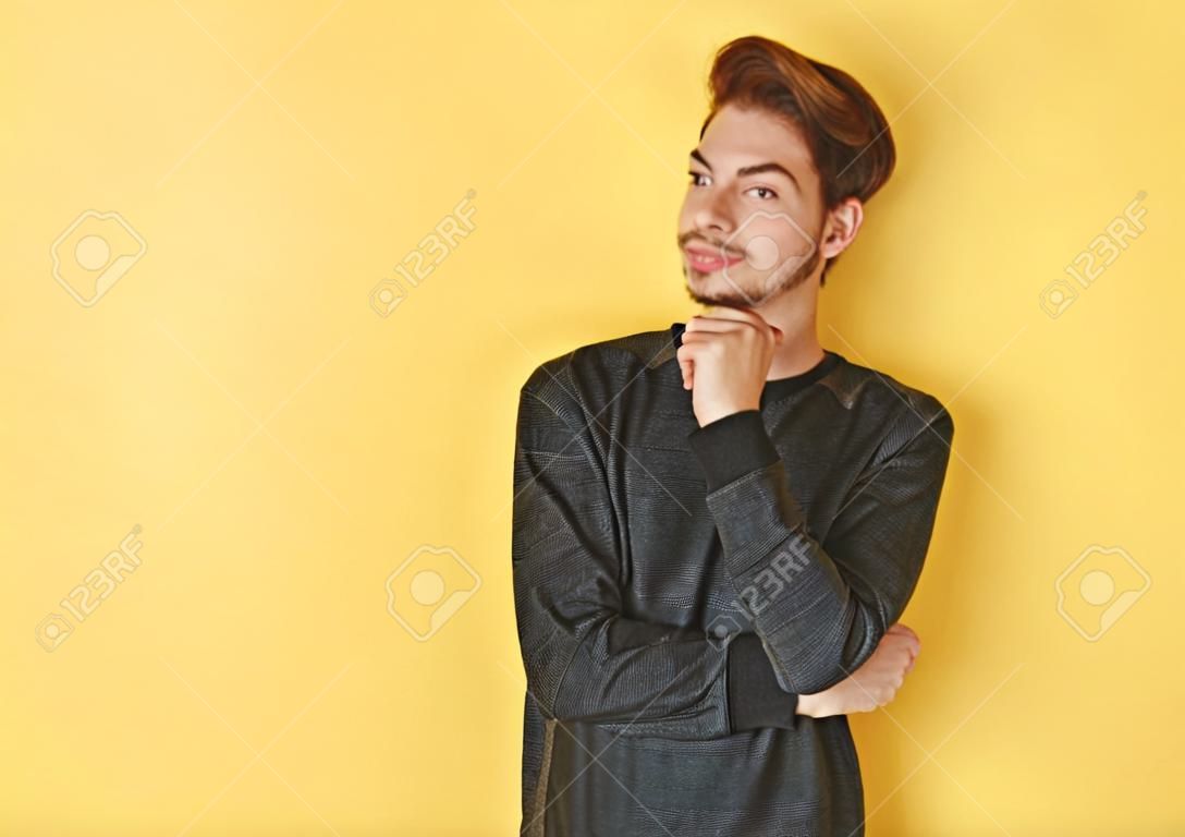 Retrato de un hombre joven elegante que se coloca contra backgroun amarillo
