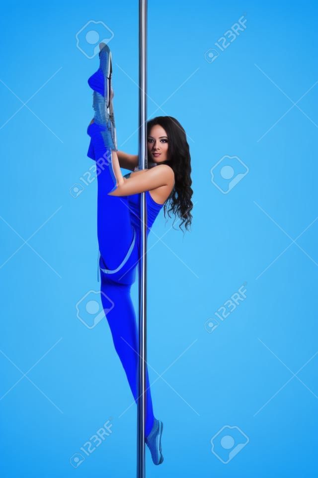 Giovane donna pole dance sottile facendo esercizio su sfondo blu