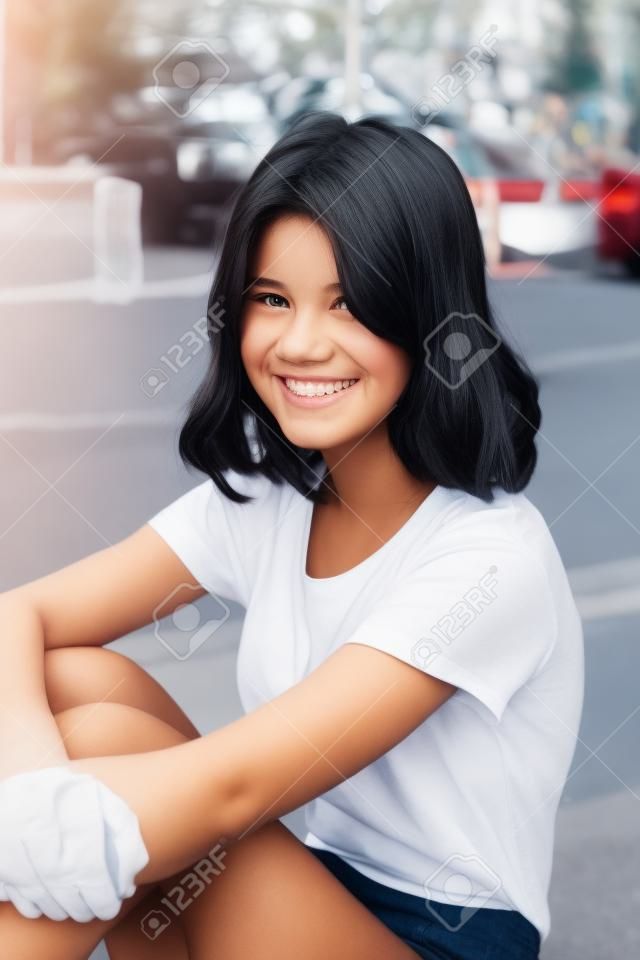 Girl fourteen years old in white are sitting on the curb