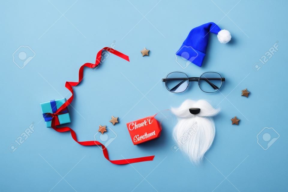 Presente de Natal ou presente para o Papai Noel Secreto com chapéu de Papai Noel, óculos e barba no fundo azul.